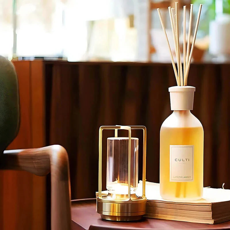 Luxuriöser Raumduft-Diffuser mit Holzstäbchen und Duftkerze auf Holztisch, elegantes Design.