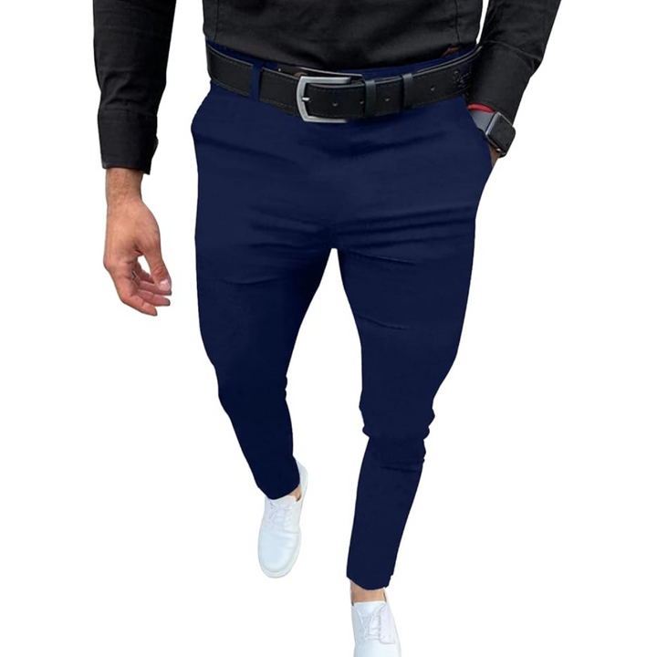 Mann in dunkelblauer Chinohose, schwarzem Hemd, weißem Sneaker, schwarzem Gürtel.