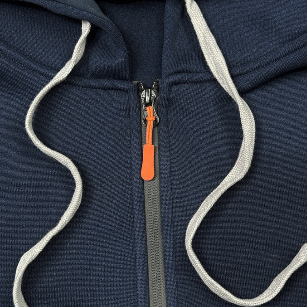 Dunkelblauer Kapuzenpullover mit Reißverschluss, graue Kordeln, orangefarbener Zipper.