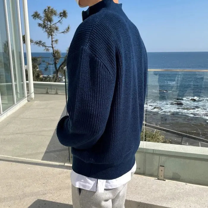 Mann im blauen Strickpullover am Meer, moderne Herrenmode, Freizeitkleidung, Küstenhintergrund.