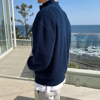 Mann im blauen Strickpullover am Meer, moderne Herrenmode, Freizeitkleidung, Küstenhintergrund.