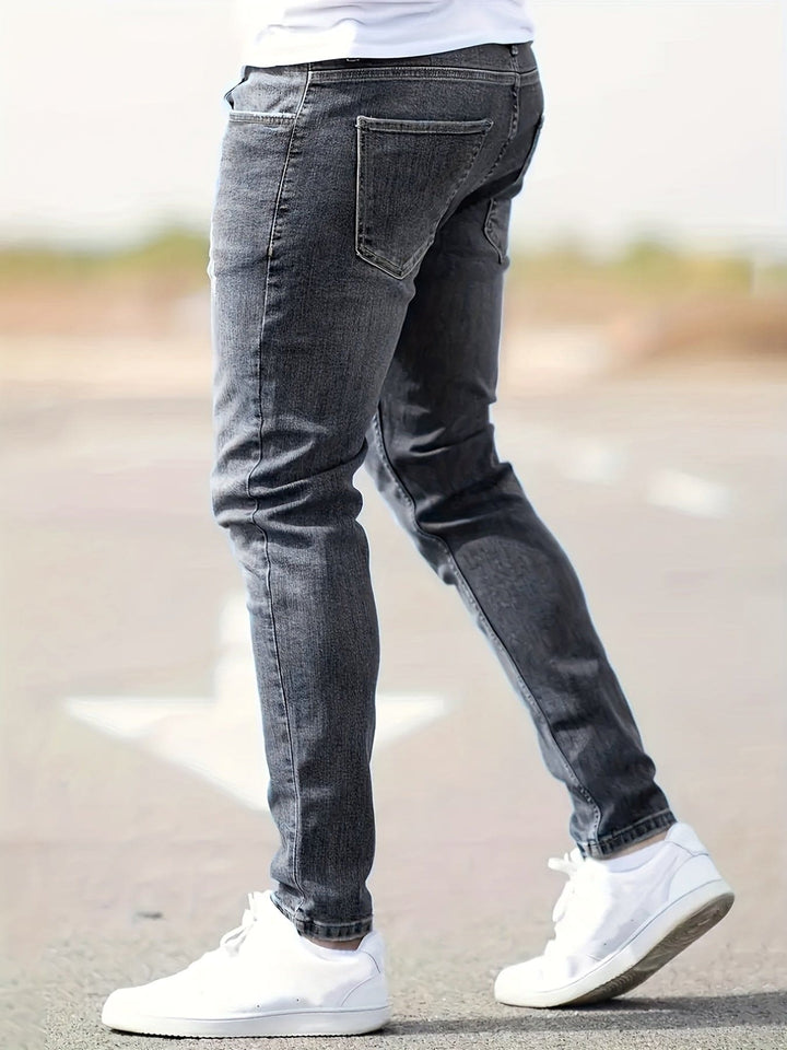 Mann in grauer Slim-Fit-Jeans und weißen Sneakern, Outdoor, modisch, lässig.