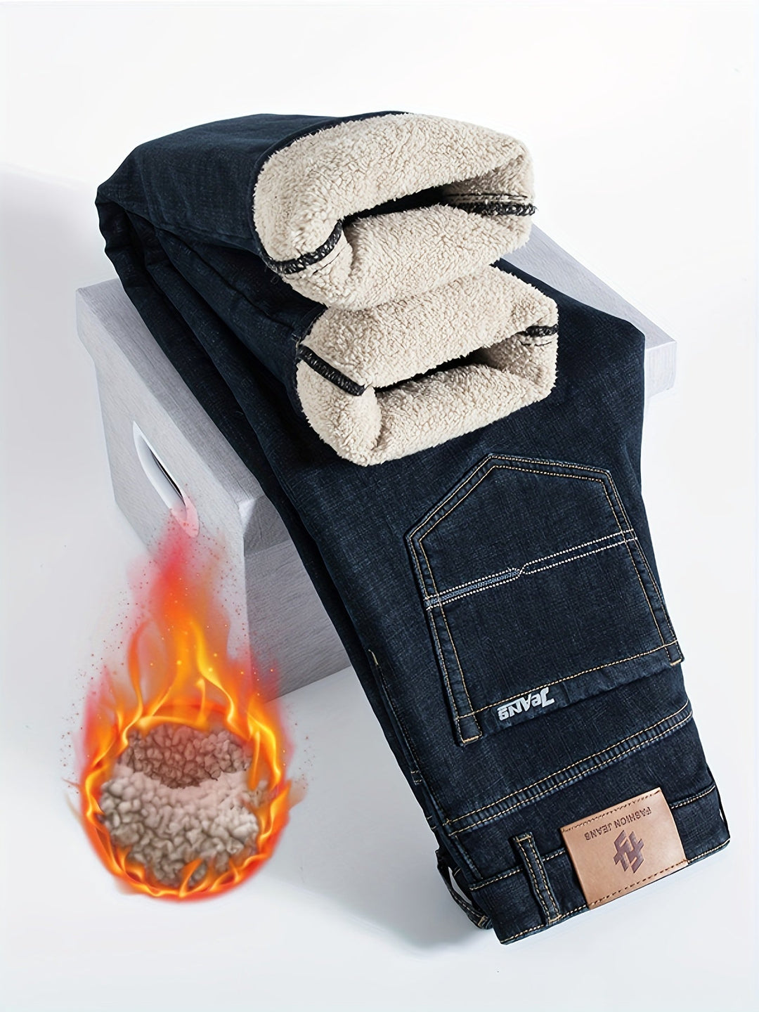 Gefütterte schwarze Jeans mit Flanellfutter, gefaltet auf Holzkiste, Flammenmotiv daneben.