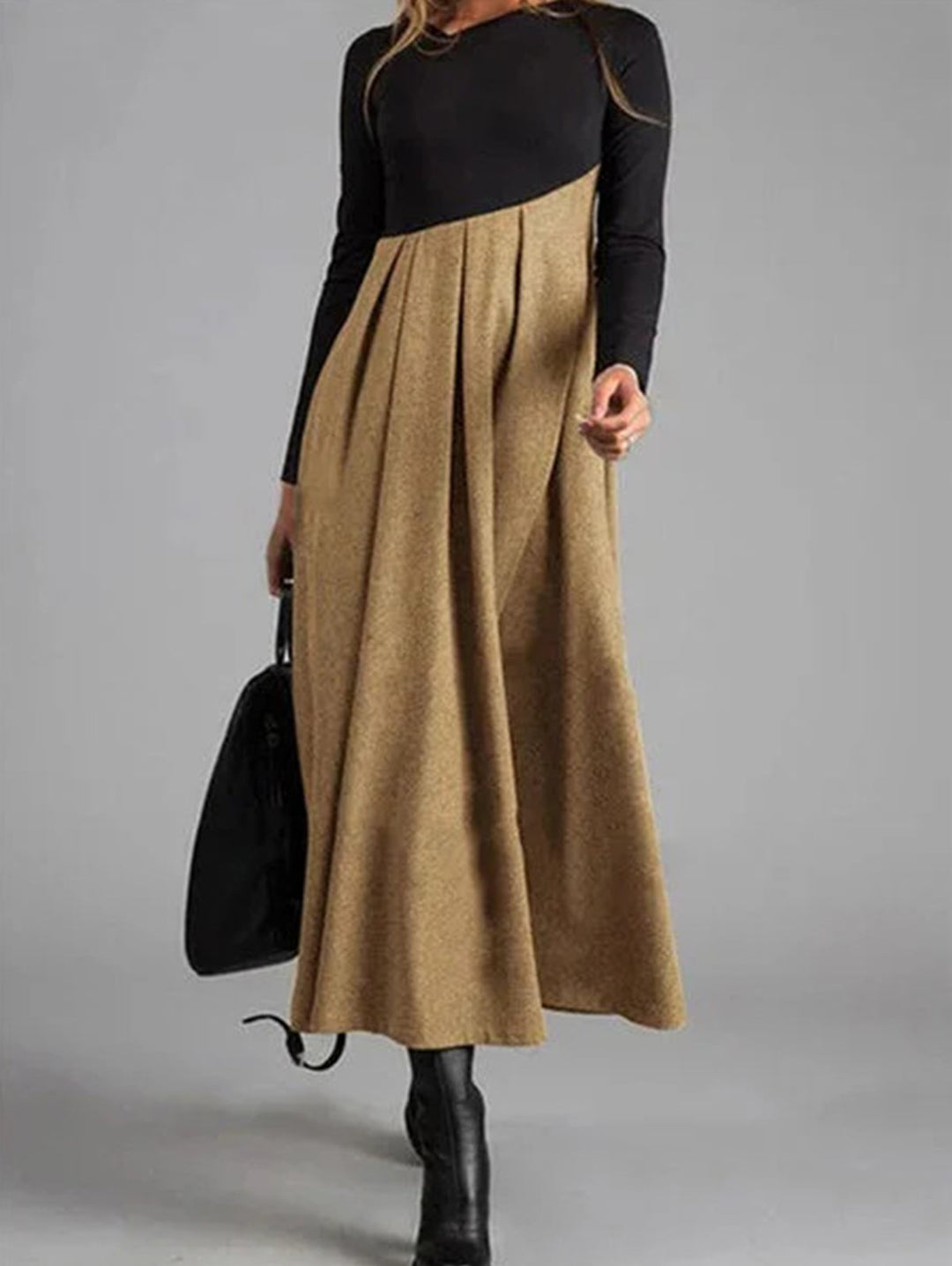 Frau in langem, zweifarbigem Kleid, schwarz und beige, mit Tasche, modisch, elegant.