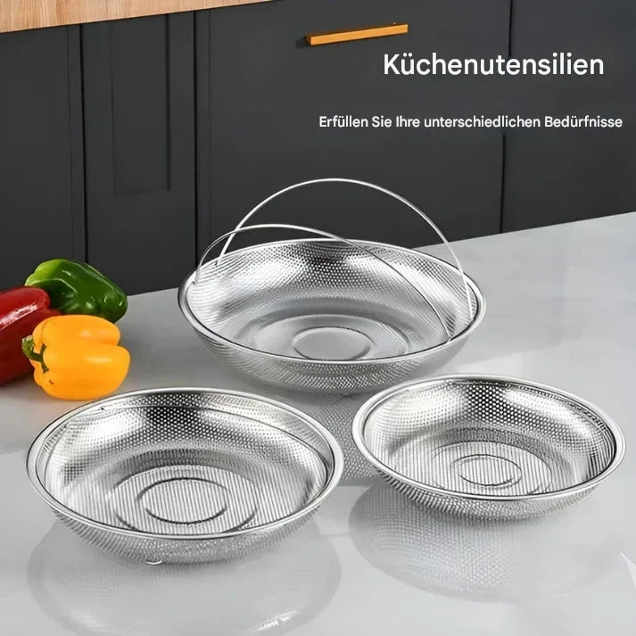 Drei silberne Edelstahl-Siebe mit Griffen auf Küchentheke, ideal für Gemüse und Obst.
