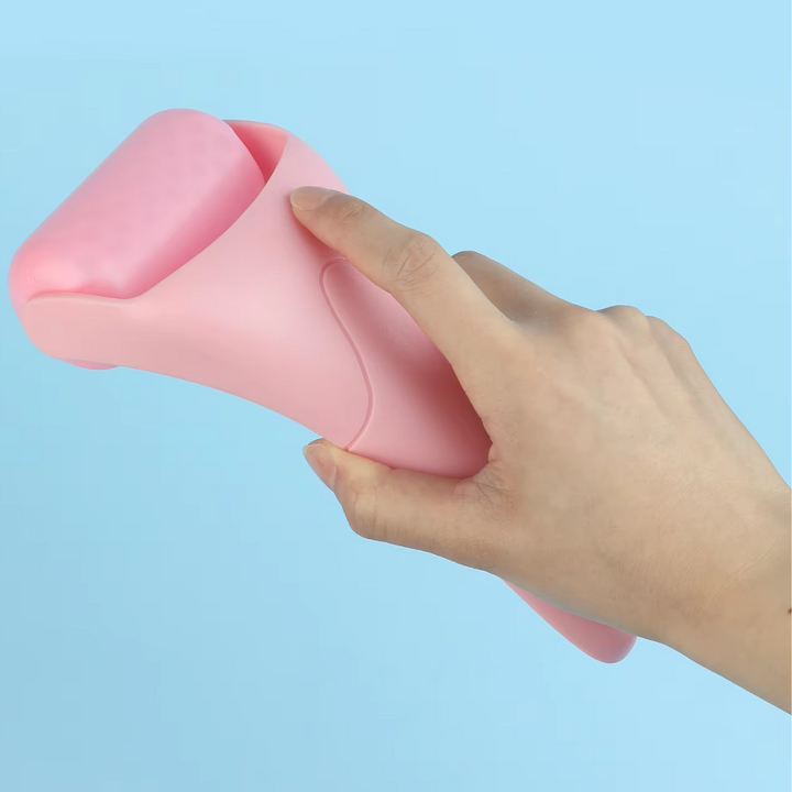 Rosa Gesichts-Eisroller aus Kunststoff, Hand hält Roller, Hautpflegewerkzeug, blauer Hintergrund.