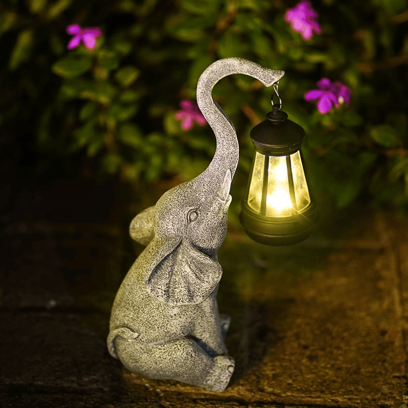 Stein-Elefant mit Laterne, Garten-Dekoration, beleuchtet, Nacht, Blumen im Hintergrund