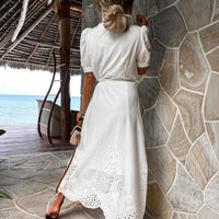 Frau in weißem Maxikleid mit Spitze am Strand, Sommermode, elegantes Design, Rückansicht.