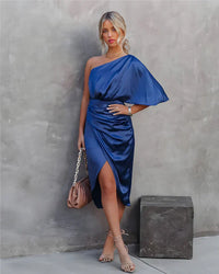 Frau in blauem, einarmigem Satin-Kleid, hält braune Handtasche, elegante Mode.