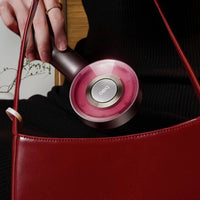 Elektrische Kopfmassagebürste mit LED-Lichttherapie, rot, Entspannungsgerät, handgehalten.