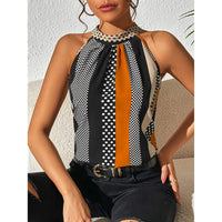 Frau trägt ärmelloses Top mit geometrischem Muster in Schwarz, Weiß und Orange.