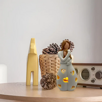 Keramikengel mit Teelicht, dekorative Figur, beige, auf Holztisch, neben Retro-Radio und Korb.