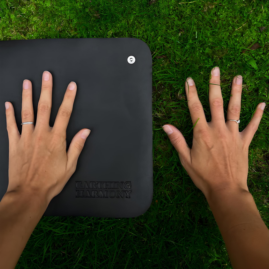 Zwei Hände auf schwarzer Erdungsmatte auf Gras, Earthing Harmony, Entspannungszubehör.