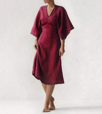 Frau in rotem Leinenkleid, knielang, mit weiten Ärmeln, minimalistisches Design.