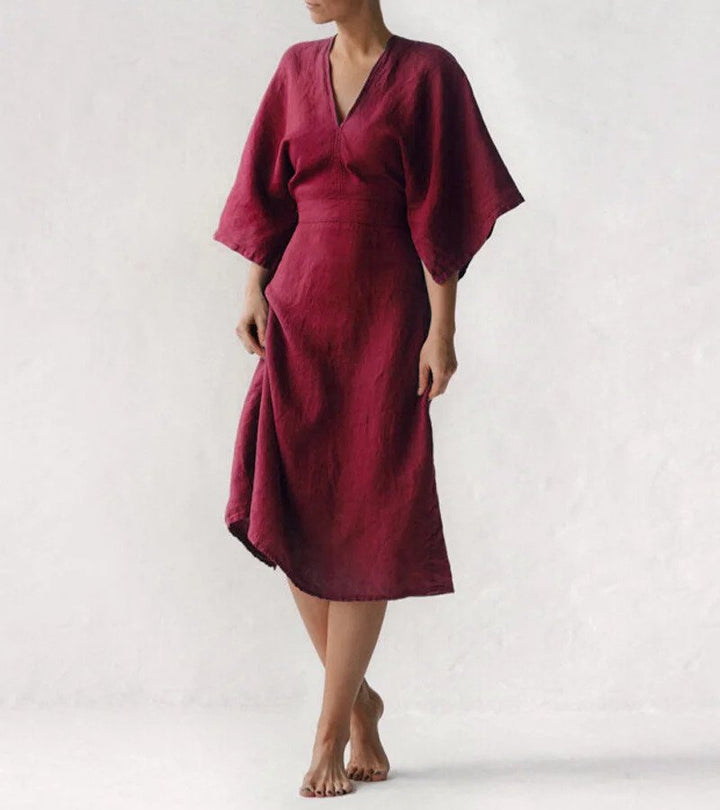Frau in rotem Leinenkleid, knielang, mit weiten Ärmeln, minimalistisches Design.
