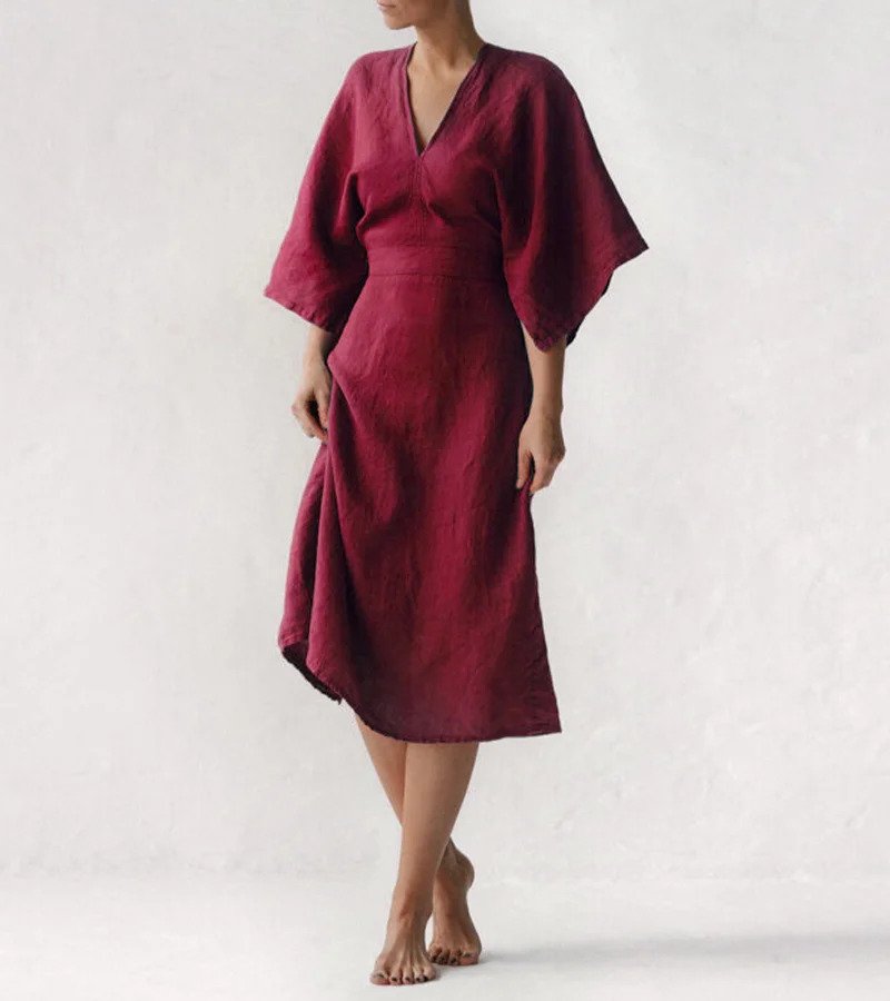 Frau in rotem Leinenkleid, knielang, mit weiten Ärmeln, minimalistisches Design.