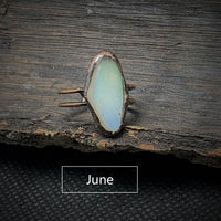 Antiker Ring mit blauem Opalstein auf Holz, handgefertigter Schmuck, Vintage-Stil.