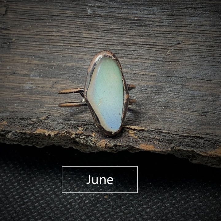 Antiker Ring mit blauem Opalstein auf Holz, handgefertigter Schmuck, Vintage-Stil.
