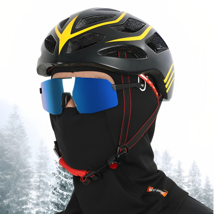 Radfahrer mit schwarzem Helm, blauer Brille und schwarzer Fleece-Gesichtsmaske im Winterwald.