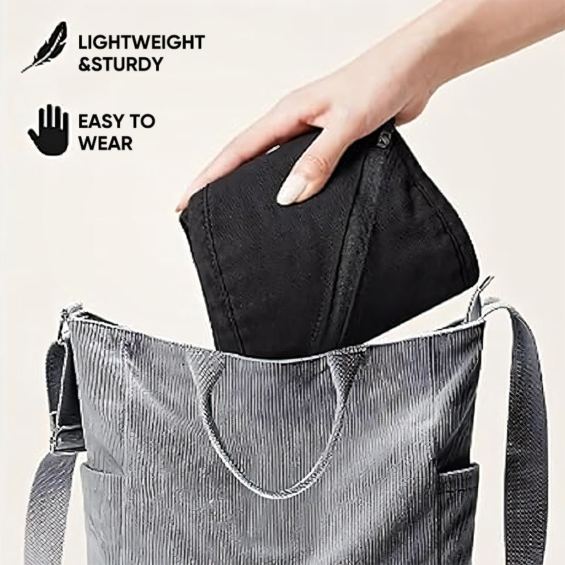 Schwarze faltbare Tasche, leicht und robust, wird in gestreifte Tragetasche gesteckt.