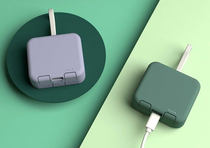 Graue und grüne faltbare Powerbanks mit USB-Kabel auf grünem Hintergrund.