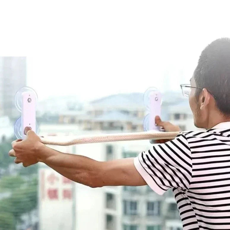 Mann reinigt Fenster mit weißem Fensterwischer und Saugnäpfen, Stadtansicht im Hintergrund.