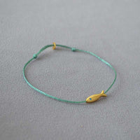 Grünes Armband mit gelbem Fischanhänger, handgefertigt, minimalistisches Schmuckdesign.
