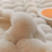 Weiches, cremefarbenes Plüschspielzeug auf strukturierter Oberfläche, Nahaufnahme.