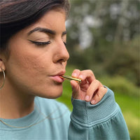 Frau mit goldener Pfeife im Freien, modisches Accessoire, Freizeitkleidung, Naturhintergrund.