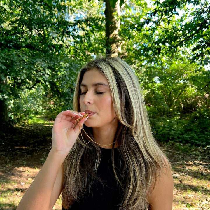 Frau im Wald mit schwarzem Top, isst Schokolade, Natur, Entspannung, Genussmoment.