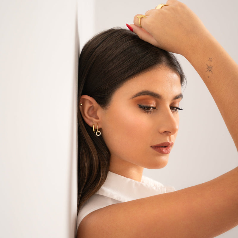 Frau mit goldenen Ohrringen und weißer Bluse, elegante Mode, Schmuck, Porträtfotografie.