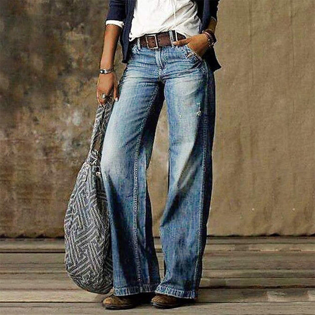 Frau in blauen, weiten Jeans mit niedriger Taille, Retro-Stil, hält gemusterte Tasche.