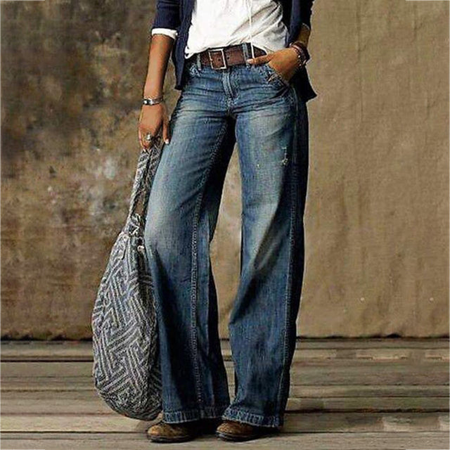 Frau in blauen, weiten Jeans mit niedriger Taille, Retro-Stil, Straße, Mode, graue Tasche.