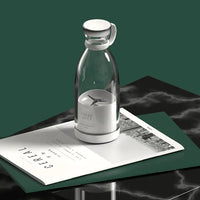 Klarer Glas-Saftmixer mit weißem Deckel auf Zeitschriften, modernes Küchengerät.