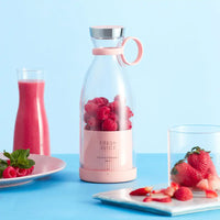 Rosa tragbarer Mixer mit frischen Beeren, ideal für Smoothies, auf blauem Hintergrund.