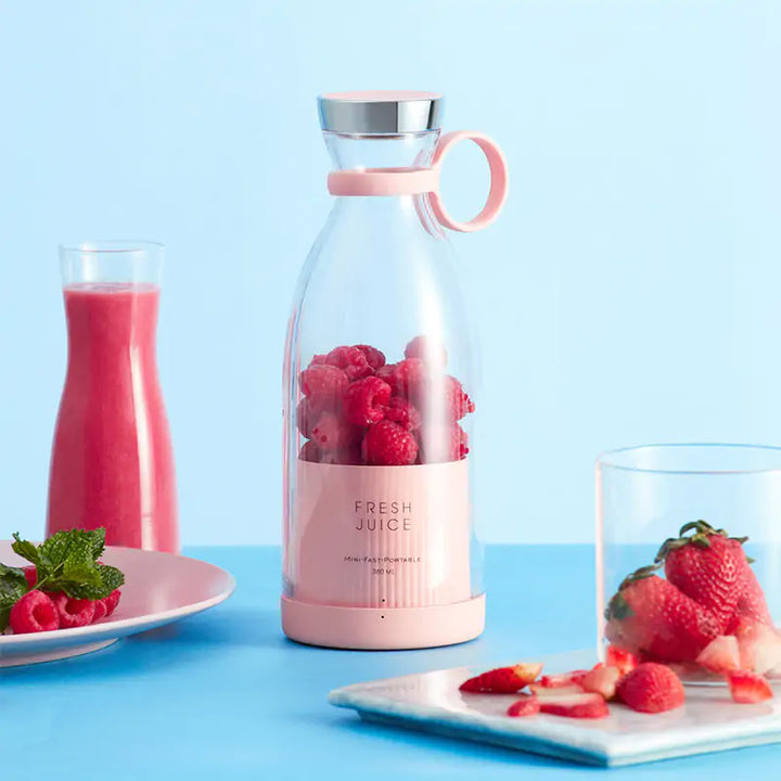 Rosa tragbarer Mixer mit frischen Beeren, ideal für Smoothies, auf blauem Hintergrund.