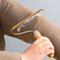 Handhobel-Fusselentferner aus Holz, entfernt Fusseln von braunem Wollpullover.