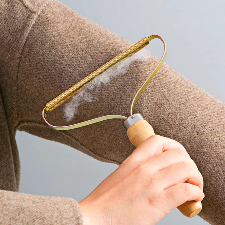 Handhobel-Fusselentferner aus Holz, entfernt Fusseln von braunem Wollpullover.