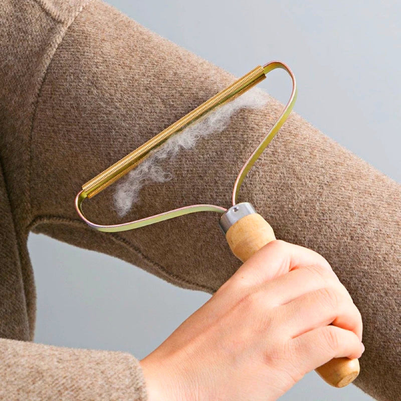 Handhobel-Fusselentferner aus Holz, entfernt Fusseln von braunem Wollpullover.