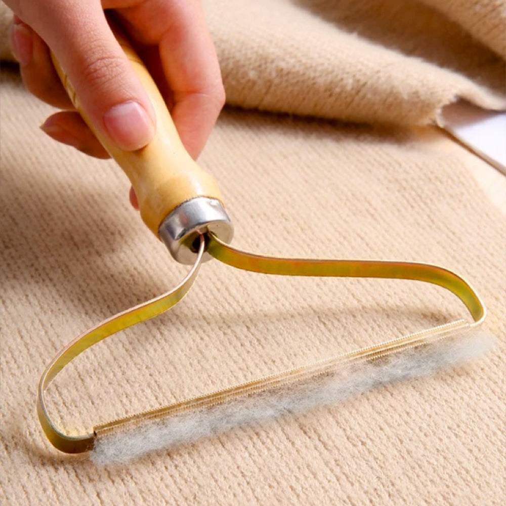 Handlicher Fusselentferner aus Holz und Metall für Kleidung, Teppiche, Sofas, beige Hintergrund.