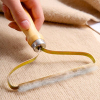 Handlicher Fusselentferner aus Holz und Metall für Kleidung, Teppiche, Sofas, beige Hintergrund.