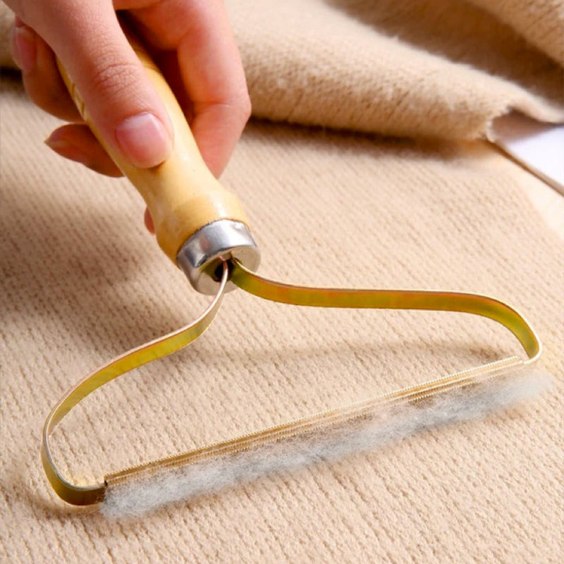 Handlicher Fusselentferner aus Holz und Metall für Kleidung, Teppiche, Sofas, beige Hintergrund.