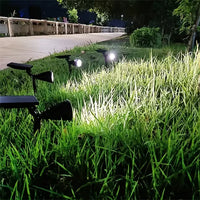 Solarbetriebene LED-Gartenstrahler beleuchten Rasen bei Nacht, energiesparende Außenbeleuchtung.