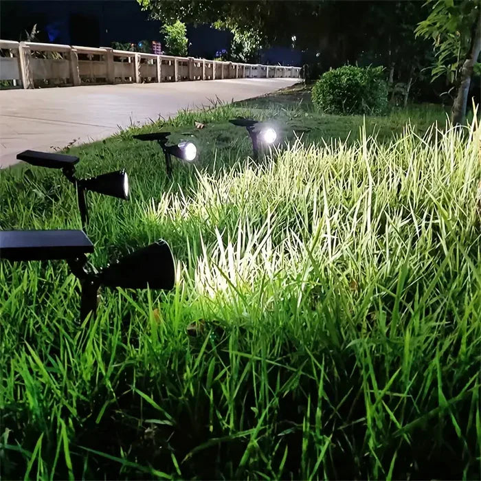 Solarbetriebene LED-Gartenstrahler beleuchten Rasen bei Nacht, energiesparende Außenbeleuchtung.