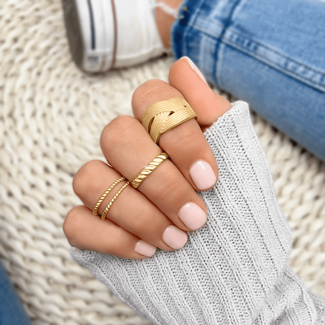 Geflochtener goldener Leinenring an Hand, modischer Schmuck, Damenaccessoire, Nahaufnahme.