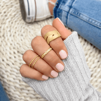 Geflochtener goldener Leinenring an Hand, modischer Schmuck, Damenaccessoire, Nahaufnahme.