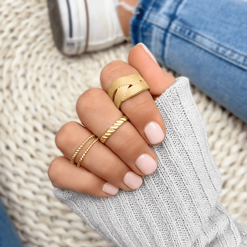 Geflochtener goldener Leinenring an Hand, modischer Schmuck, Damenaccessoire, Nahaufnahme.