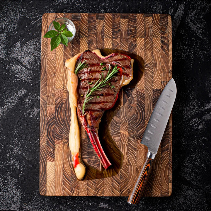Rohes Tomahawk-Steak auf Holzbrett mit Messer und Rosmarin, schwarzer Hintergrund.