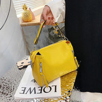 Gelbe Lederhandtasche mit Reißverschlüssen, modisch, Damenaccessoire, auf silbernem Tisch.