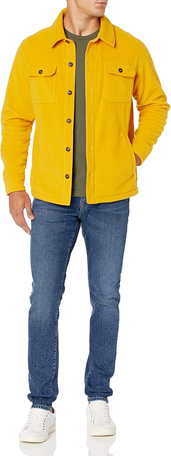 Mann in gelber Fleecejacke, blauer Jeans und weißen Sneakers, lässige Herrenmode.